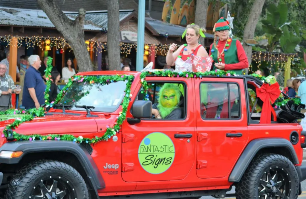 grinch driving red jeep truck decorated in Christmas décor in Christmas parade