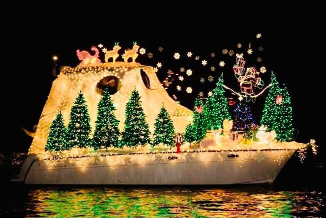 boat on water decorated with fake snow, Christmas trees, and lights