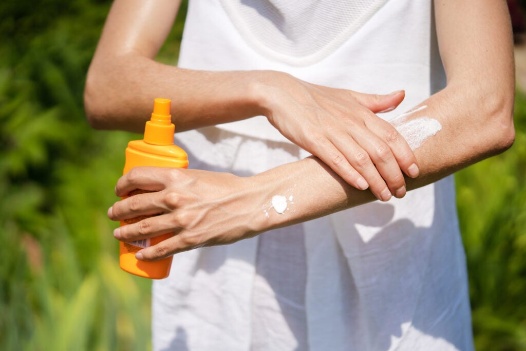person applying sunscreen to their arms
