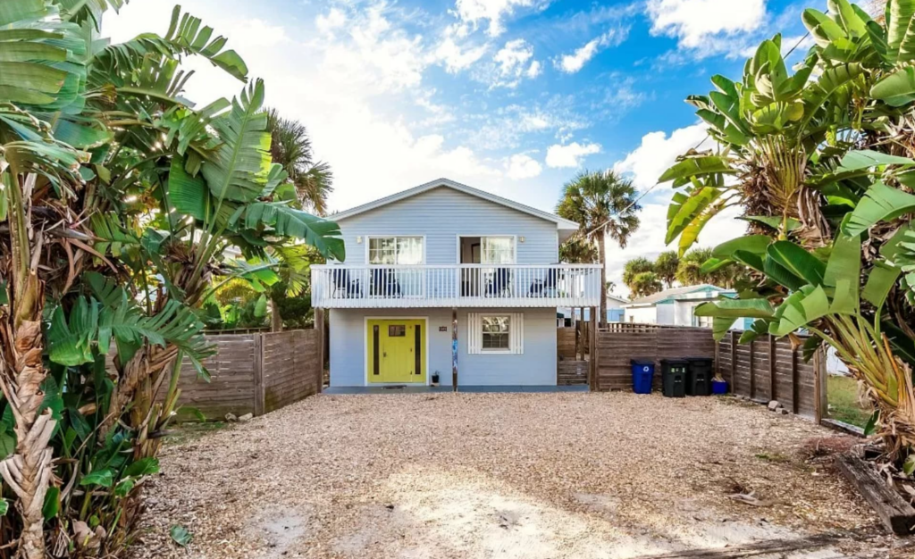 adorable blue house with yellow door and lots of palm trees surrounding, 5 min walk to the beach