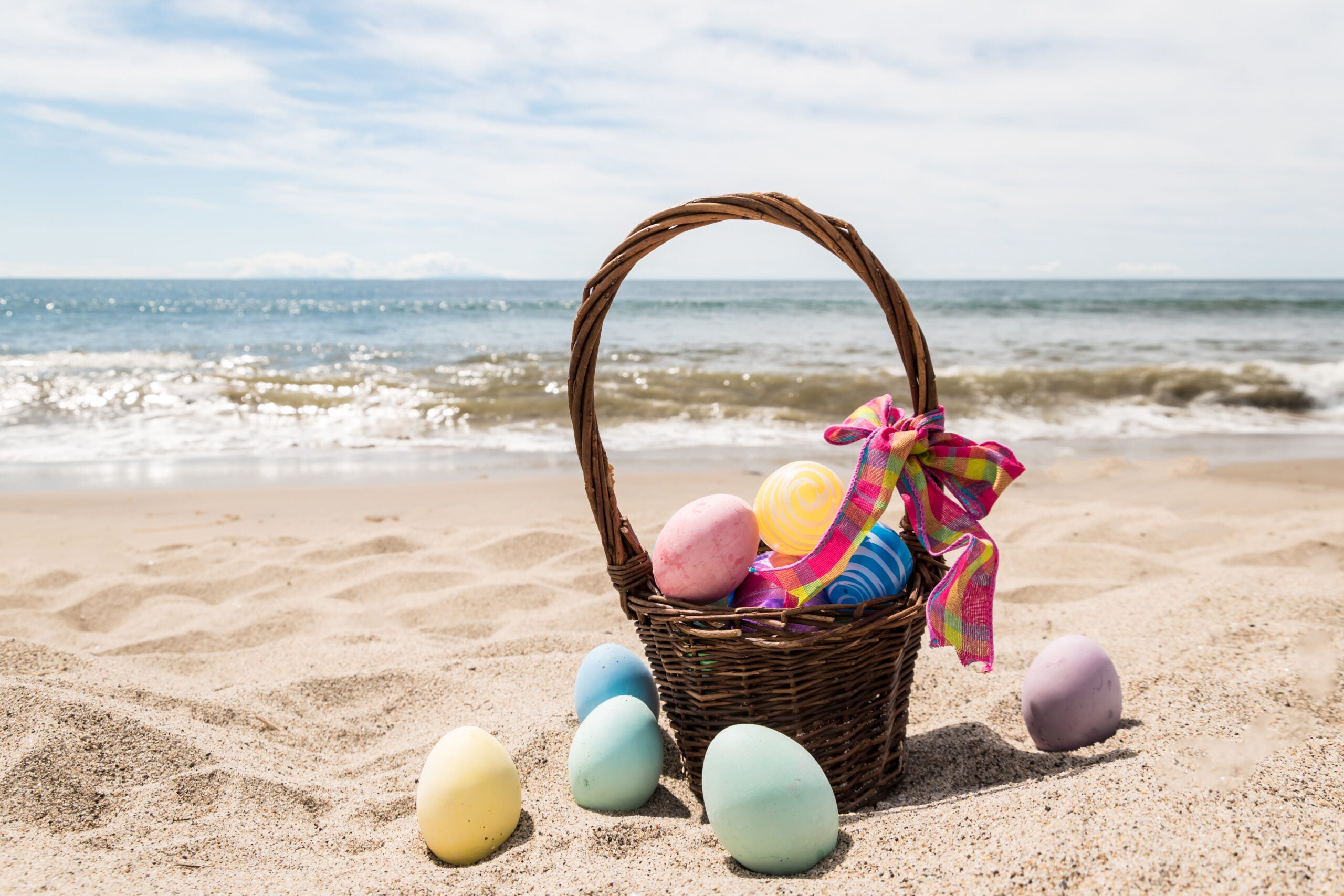 basket full of easter eggs at the beach