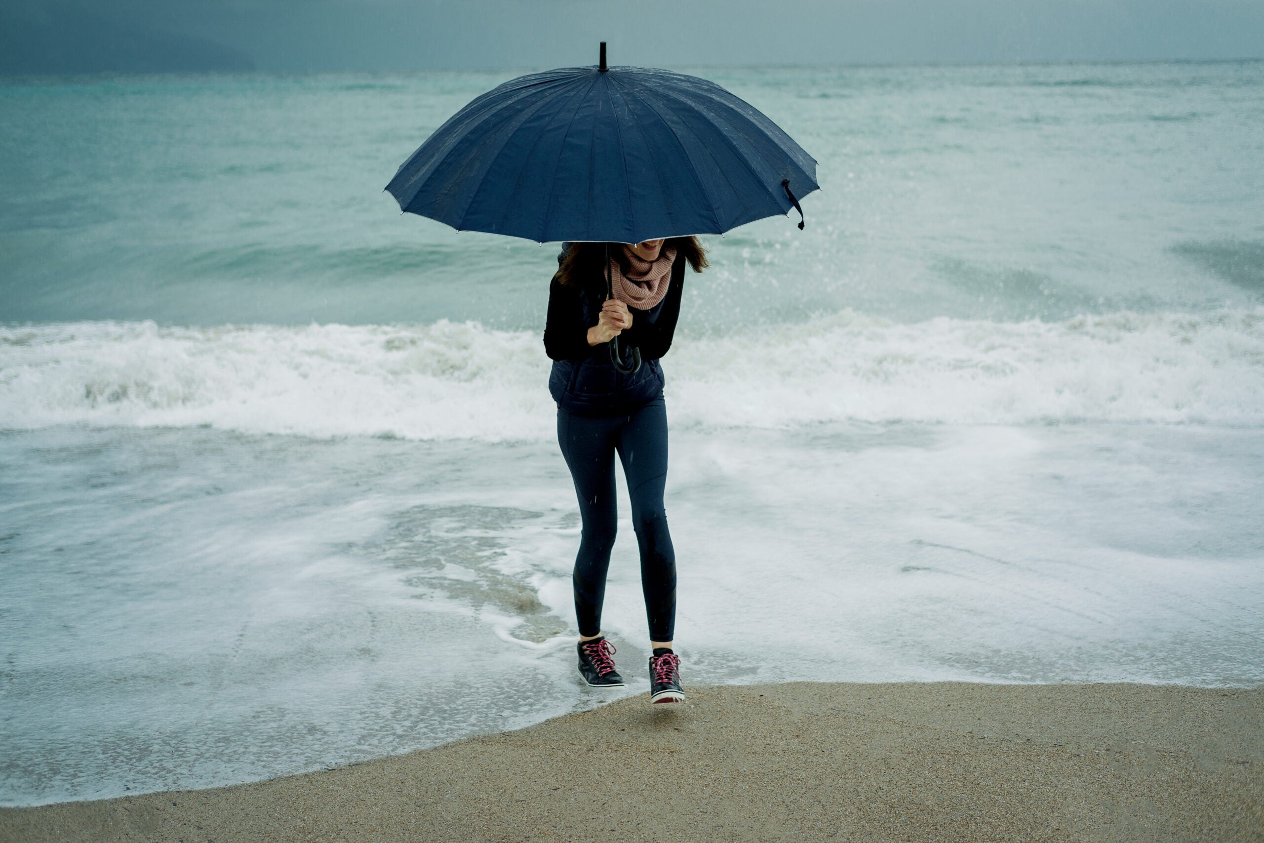woman at beach on rainy gloomy day with umbrella on rainy day in new smyrna beach